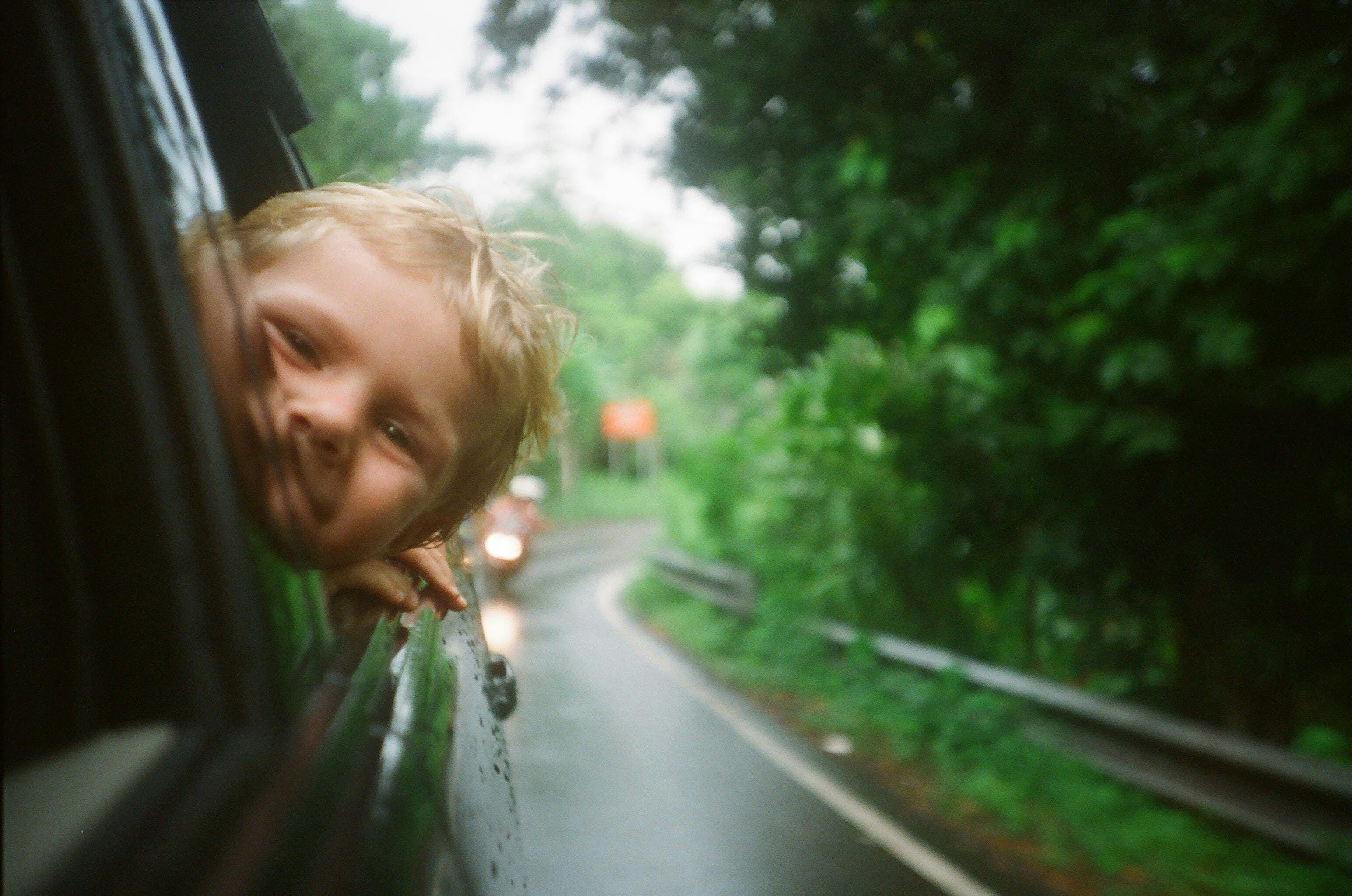 Ein Kind streckt den Kopf aus dem Autofenster und lächelt in die Kamera