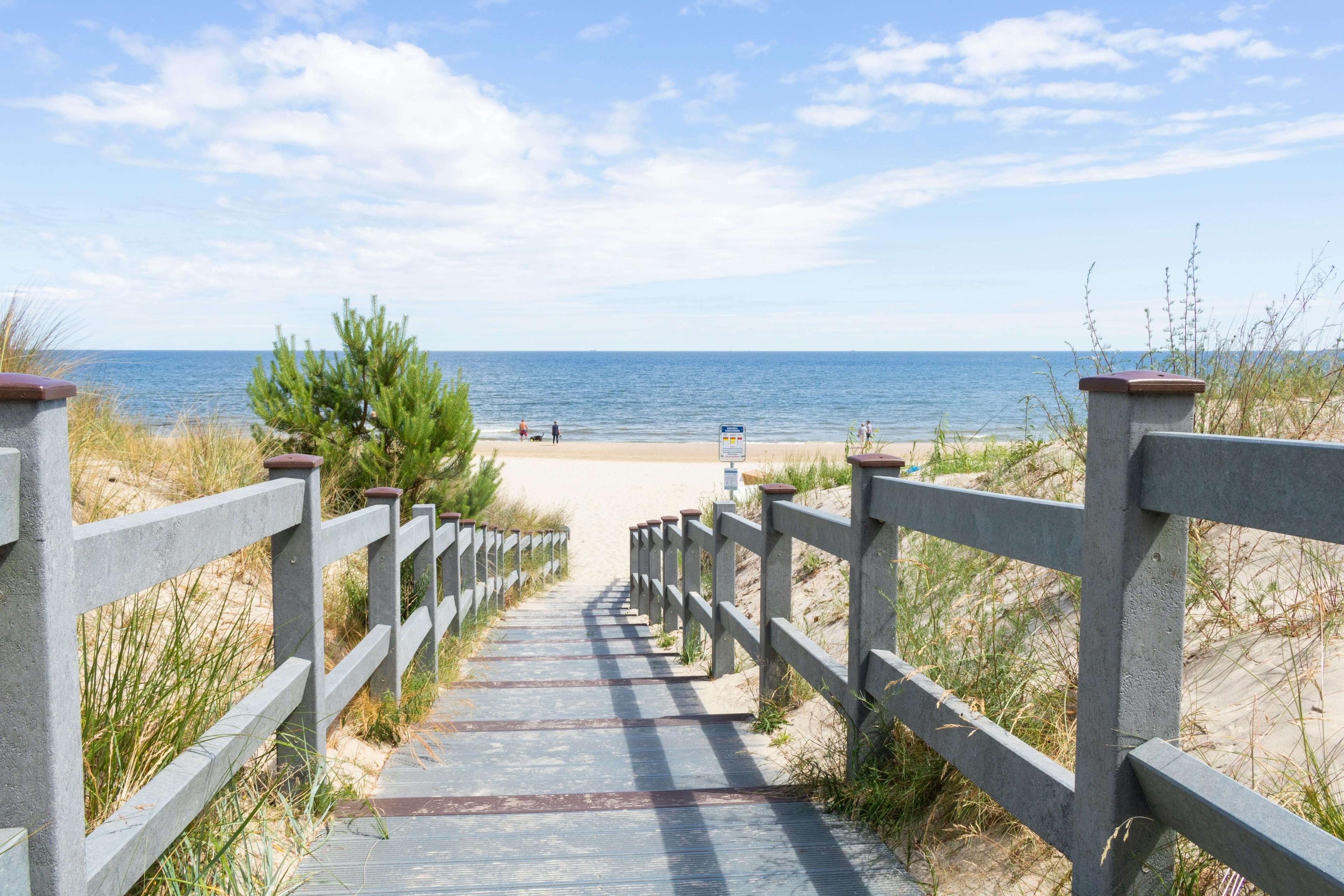 Umzäunter Weg über eine Düne zum Meer
