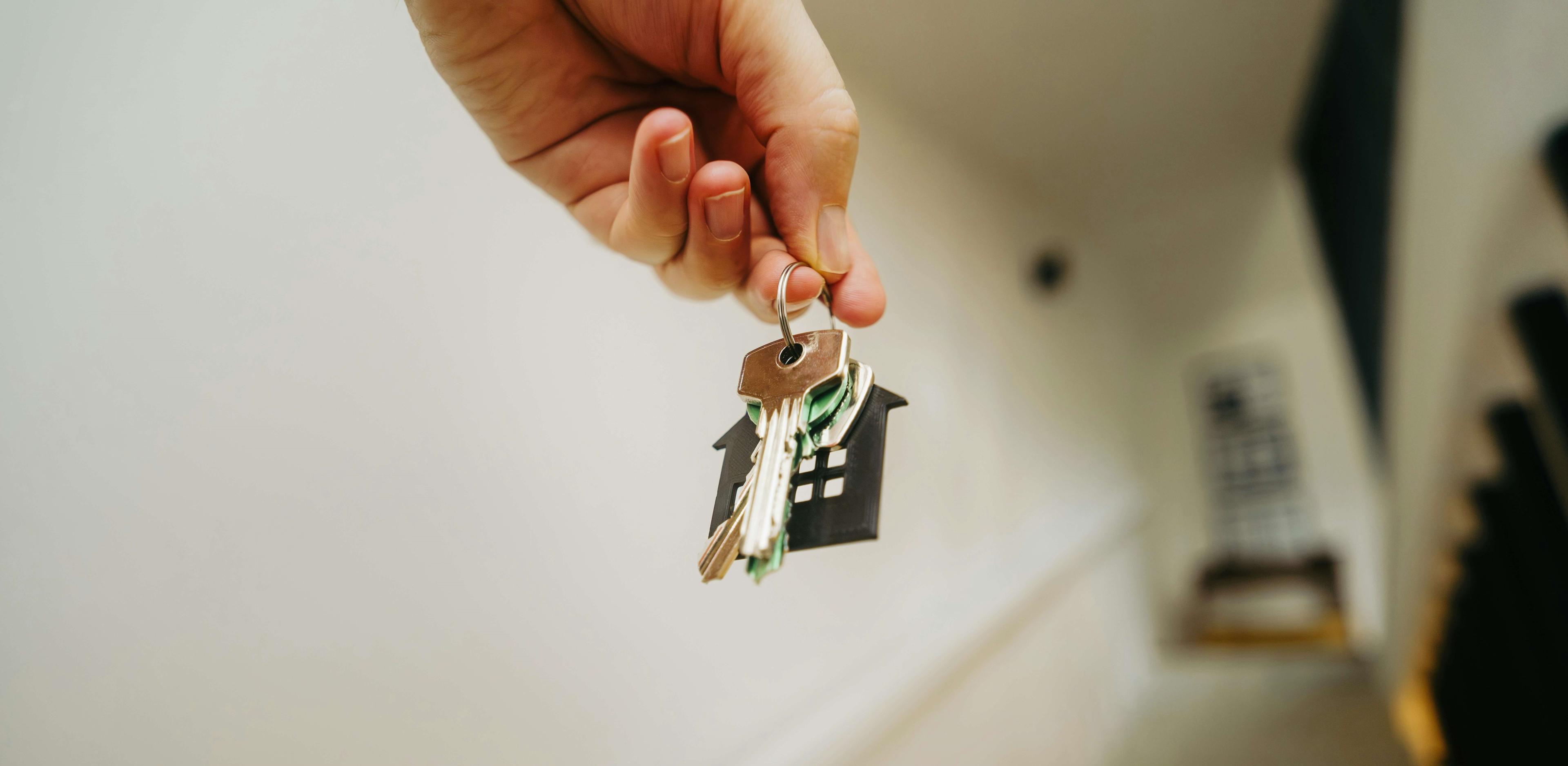 Ein Treppenhaus mit einer Hand, die einen Wohnungsschlüssel hält im Vordergrund
