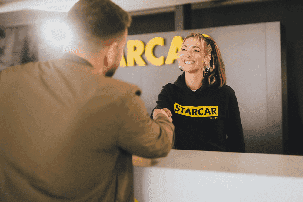 Smiling STARCAR employee shaking hands with a customer.