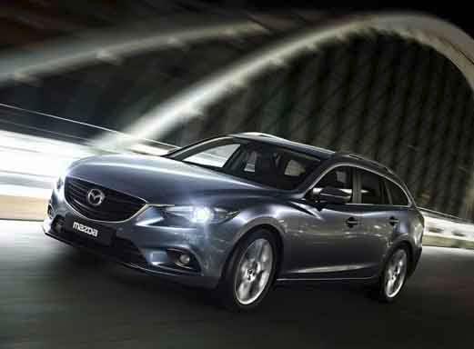 Silver Mazda 6 driving over an illuminated bridge.