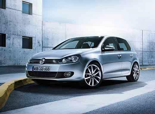 Silver VW Golf rental car parked on asphalt near a yellow barrier.