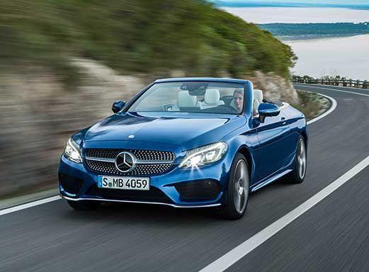 Blaues Mercedes Benz Cabrio auf einer Küstenstraße.